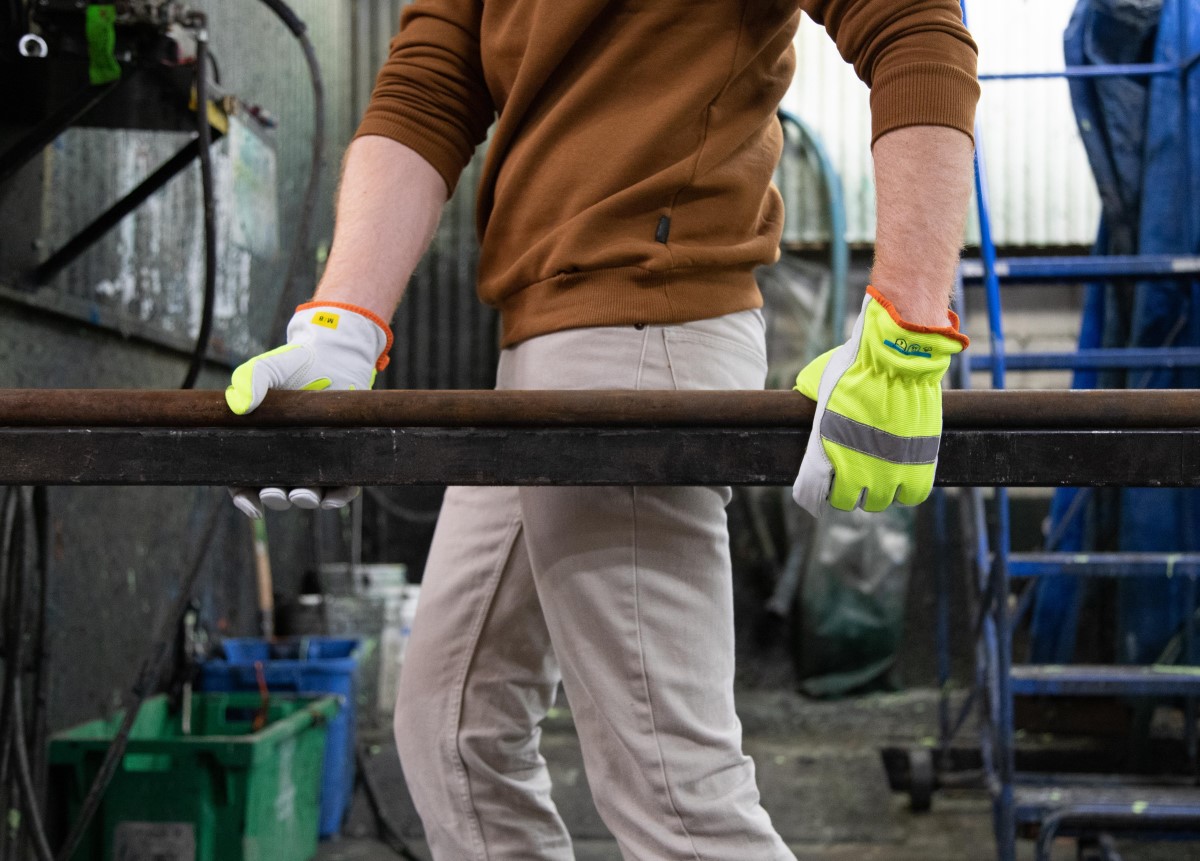 man holding steel beams while wearing high-visibility work gloves