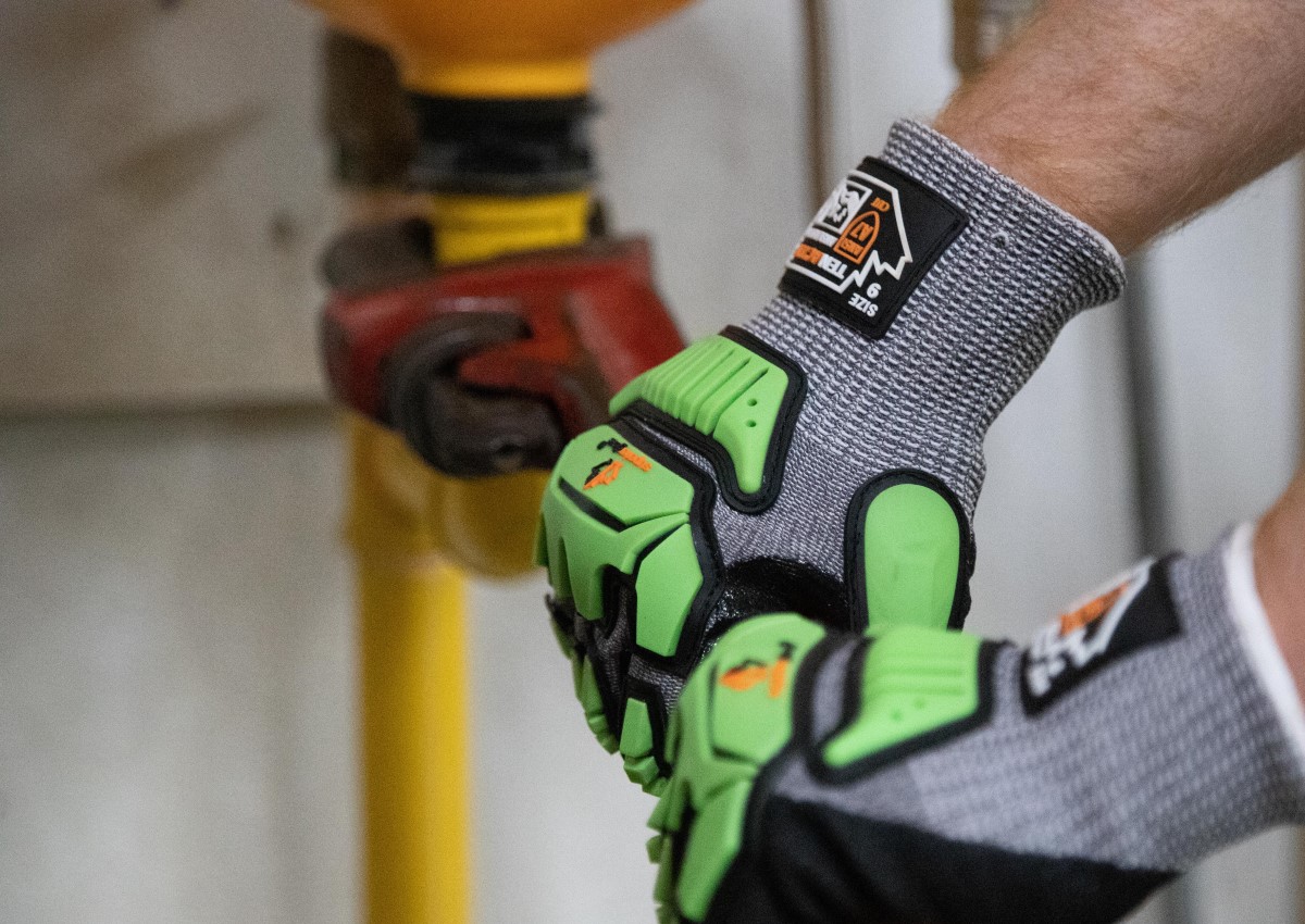 person wearing high-viz impact resistant gloves holding a wrench