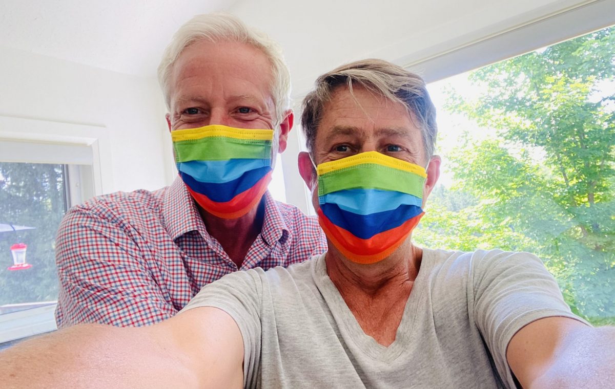 two people taking a selfie while wearing rainbow masks