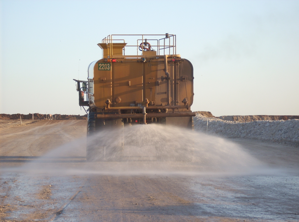 road haul truck spraying down dirt at an open pit mine
