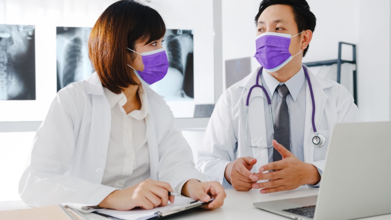 doctors wearing masks and discussing long covid with xrays of lungs in the background