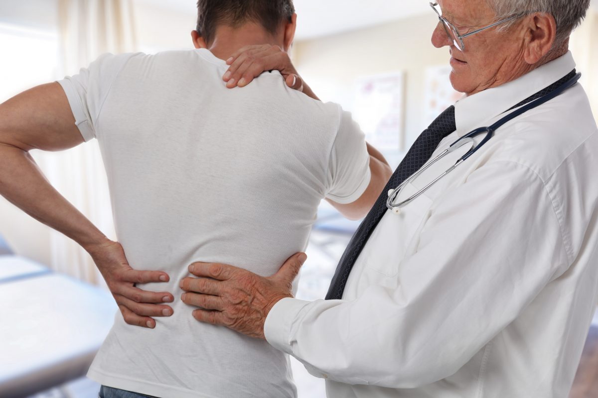 doctor feeling a man's lower back to find pain points