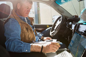 man sitting in truck using laptop to track plume modeling